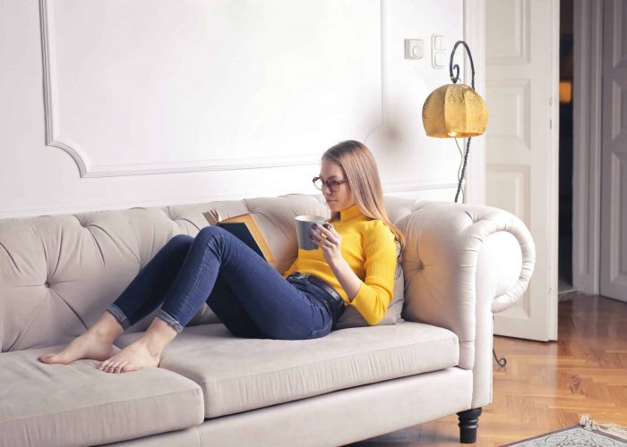 woman-sitting-on-white-couch-while-reading-a-book-3767382